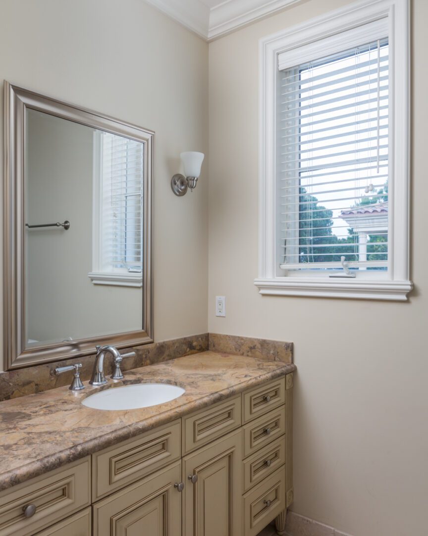 A bathroom with a sink, mirror and window.