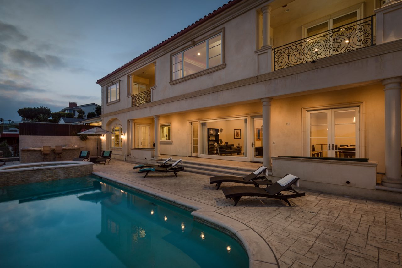 A pool with chairs and tables in the back yard